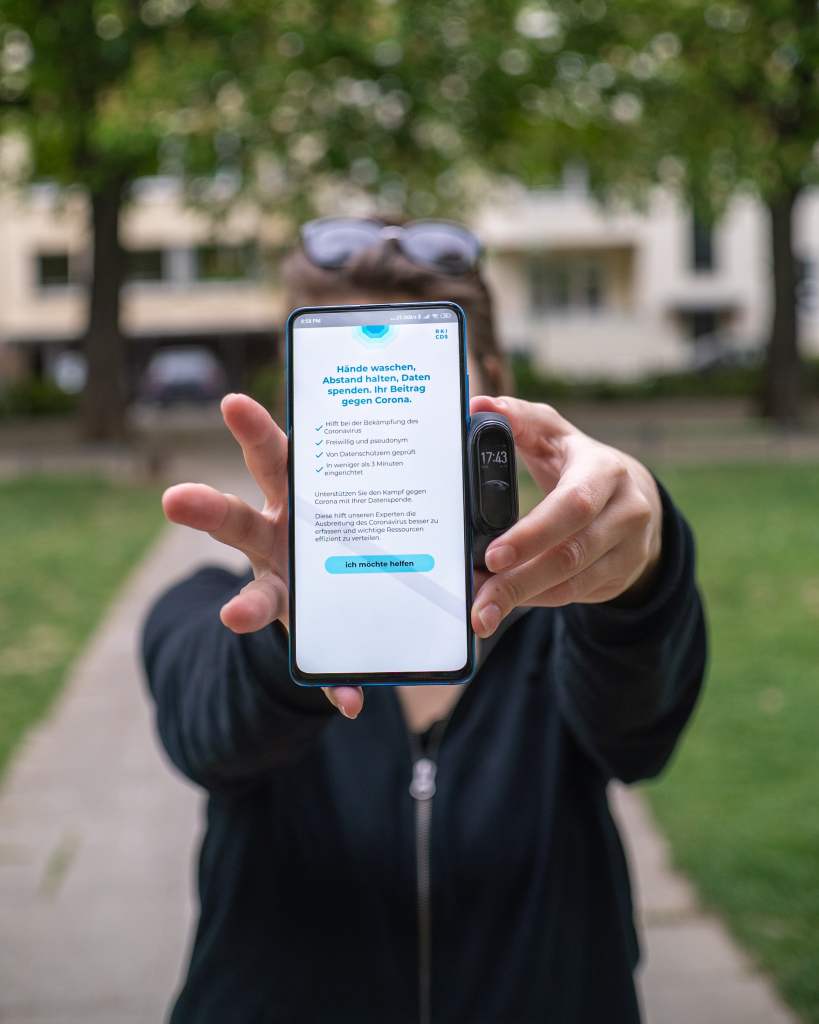 Person holding up smartphone displaying the German Robert Koch Institute Corona-Datenspende (Corona Data Donation) app, which was one of the few COVID-19 tracking apps that was praised for effective data privacy practices. Photo by Mika Baumeister on Unsplash.com.
